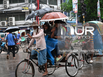 A rickshaw puller with a passenger makes his way along a street during heavy rainfall in Dhaka, Bangladesh, on September 15, 2024. (