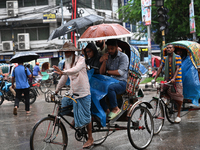 A rickshaw puller with a passenger makes his way along a street during heavy rainfall in Dhaka, Bangladesh, on September 15, 2024. (