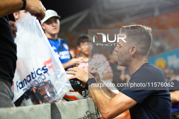 Houston Dynamo coach Ben Olsen signs a soccer ball for young fans after a match between Houston Dynamo and Real Salt Lake at Shell Energy St...