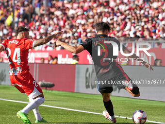 Portu of Girona challenges Pau Cubarsi of FC Barcelona for possession during the La Liga EA SPORTS match at Estadi Montilivi in Girona, Spai...