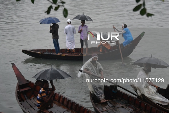 Passengers cross the Buriganga River, holding umbrellas during a drizzle in Dhaka, Bangladesh, on September 15, 2024. 