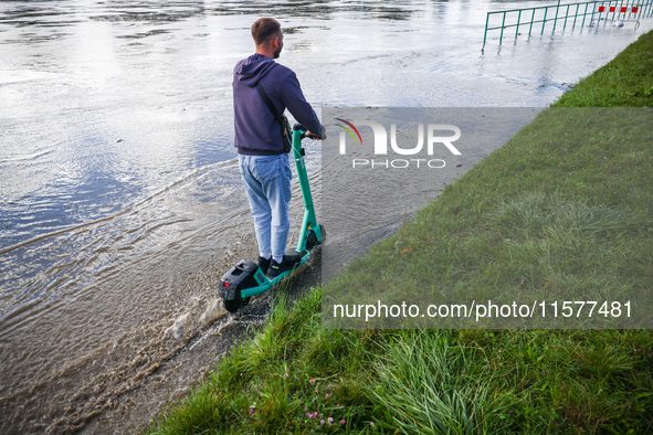 A person rides electric scooter after heavy rainfall raised  the level of the Vistula River flooding a part of the boulvards in Krakow, Pola...