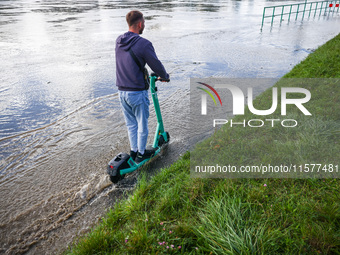 A person rides electric scooter after heavy rainfall raised  the level of the Vistula River flooding a part of the boulvards in Krakow, Pola...