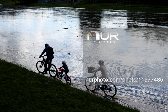 A family rides bikes after heavy rainfall raised the level of the Vistula River flooding a part of the boulvards in Krakow, Poland on Septem...