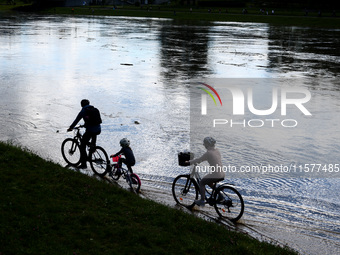 A family rides bikes after heavy rainfall raised the level of the Vistula River flooding a part of the boulvards in Krakow, Poland on Septem...