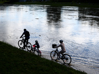 A family rides bikes after heavy rainfall raised the level of the Vistula River flooding a part of the boulvards in Krakow, Poland on Septem...