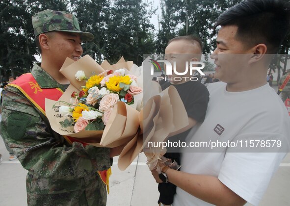 A child presents flowers to new recruits at the militia training base in Yongnian district of Handan, China, on September 14, 2024. 