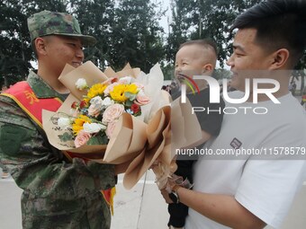 A child presents flowers to new recruits at the militia training base in Yongnian district of Handan, China, on September 14, 2024. (