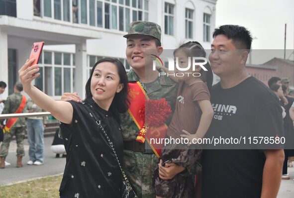 A recruit poses for a photo with his family at the militia training base in Yongnian district of Handan, China, on September 14, 2024. 