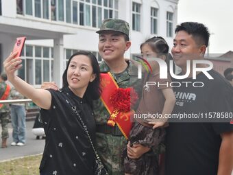 A recruit poses for a photo with his family at the militia training base in Yongnian district of Handan, China, on September 14, 2024. (