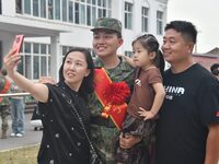 A recruit poses for a photo with his family at the militia training base in Yongnian district of Handan, China, on September 14, 2024. (