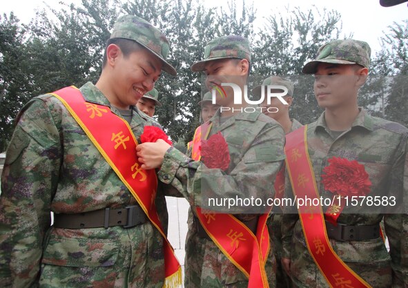 A recruit wears a red flower for his comrades at a militia training base in Yongnian district in Handan, China, on September 14, 2024. 