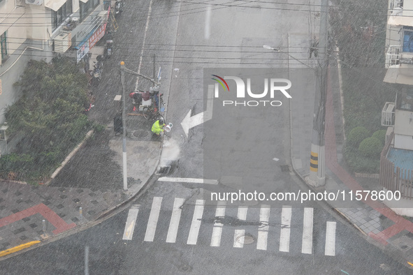 A sanitation worker cleans an urban sewer to prevent water from flooding at a junction in Yangpu district in Shanghai, China, on September 1...