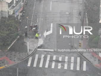 A sanitation worker cleans an urban sewer to prevent water from flooding at a junction in Yangpu district in Shanghai, China, on September 1...