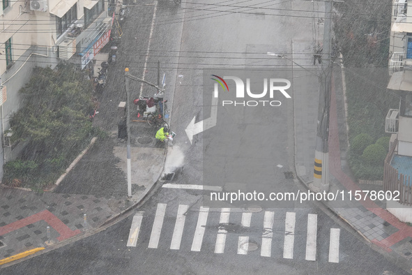 A sanitation worker cleans an urban sewer to prevent water from flooding at a junction in Yangpu district in Shanghai, China, on September 1...