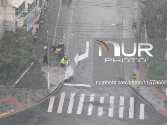 A sanitation worker cleans an urban sewer to prevent water from flooding at a junction in Yangpu district in Shanghai, China, on September 1...