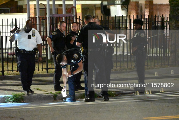 Police place evidence markers and set up crime scene tape at the scene where two people are shot. Two people are shot in Brooklyn, New York,...