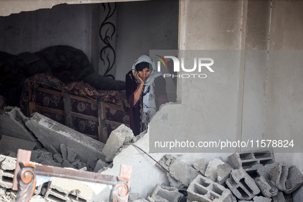 A Palestinian woman inspects her home, which is damaged by an Israeli airstrike on a house in Nuseirat, central Gaza Strip, on September 16,...