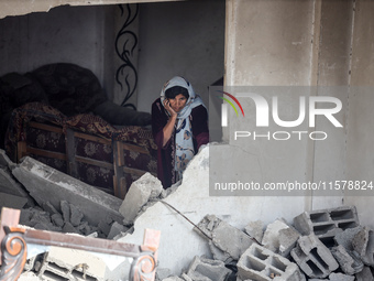 A Palestinian woman inspects her home, which is damaged by an Israeli airstrike on a house in Nuseirat, central Gaza Strip, on September 16,...