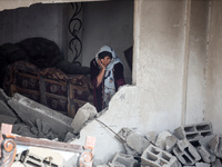 A Palestinian woman inspects her home, which is damaged by an Israeli airstrike on a house in Nuseirat, central Gaza Strip, on September 16,...