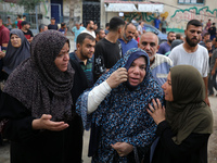 Mourners wait to bury the bodies of members of the Al-Qassas family in the cemetery in the Nuseirat refugee camp for Palestinian refugees in...