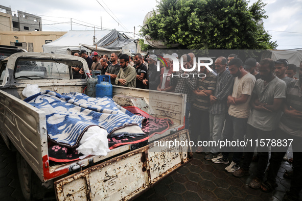 Men recite prayers over the corpses of people killed in an overnight Israeli strike in the yard of the Al-Aqsa Martyrs hospital in Deir el-B...