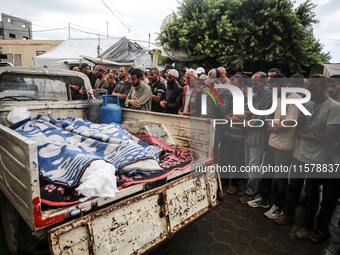 Men recite prayers over the corpses of people killed in an overnight Israeli strike in the yard of the Al-Aqsa Martyrs hospital in Deir el-B...