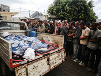 Men recite prayers over the corpses of people killed in an overnight Israeli strike in the yard of the Al-Aqsa Martyrs hospital in Deir el-B...