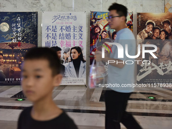 People walk past movie posters at a cinema in Fuyang, China, on September 16, 2024. (