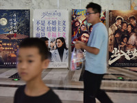 People walk past movie posters at a cinema in Fuyang, China, on September 16, 2024. (