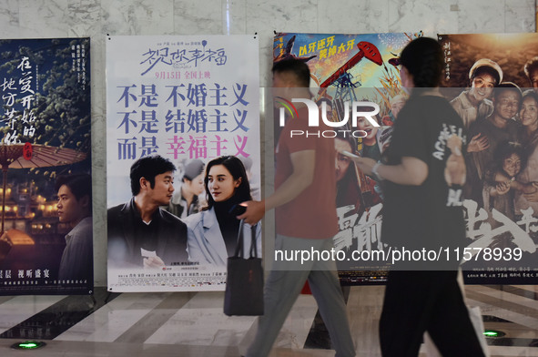 People walk past movie posters at a cinema in Fuyang, China, on September 16, 2024. 