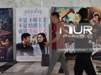 People walk past movie posters at a cinema in Fuyang, China, on September 16, 2024. (