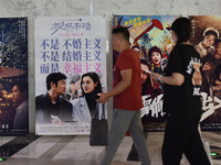 People walk past movie posters at a cinema in Fuyang, China, on September 16, 2024. (