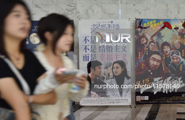 People walk past movie posters at a cinema in Fuyang, China, on September 16, 2024. 