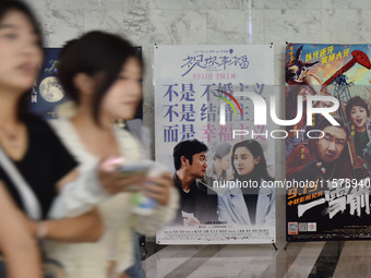 People walk past movie posters at a cinema in Fuyang, China, on September 16, 2024. (