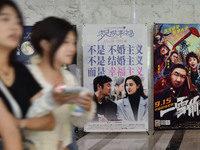 People walk past movie posters at a cinema in Fuyang, China, on September 16, 2024. (