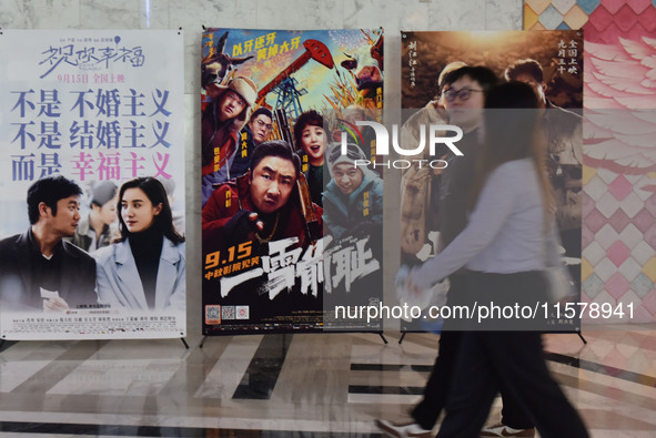 People walk past movie posters at a cinema in Fuyang, China, on September 16, 2024. 