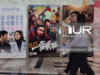 People walk past movie posters at a cinema in Fuyang, China, on September 16, 2024. (