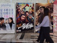 People walk past movie posters at a cinema in Fuyang, China, on September 16, 2024. (