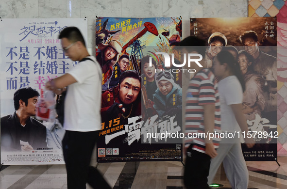 People walk past movie posters at a cinema in Fuyang, China, on September 16, 2024. 