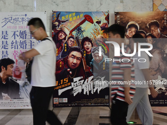 People walk past movie posters at a cinema in Fuyang, China, on September 16, 2024. (