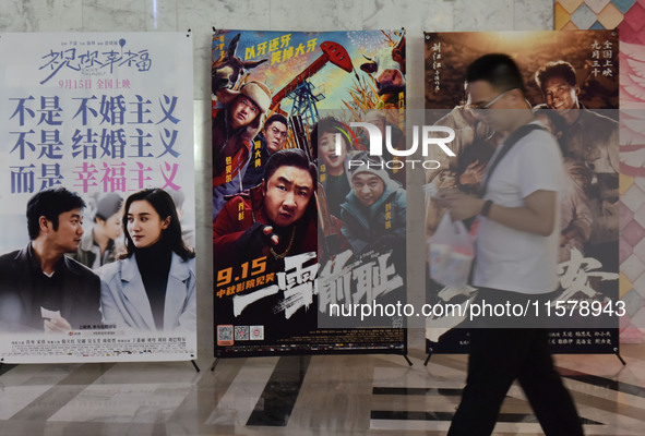 People walk past movie posters at a cinema in Fuyang, China, on September 16, 2024. 