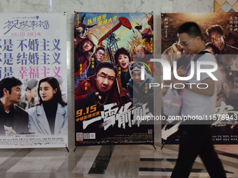 People walk past movie posters at a cinema in Fuyang, China, on September 16, 2024. (