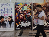 People walk past movie posters at a cinema in Fuyang, China, on September 16, 2024. (