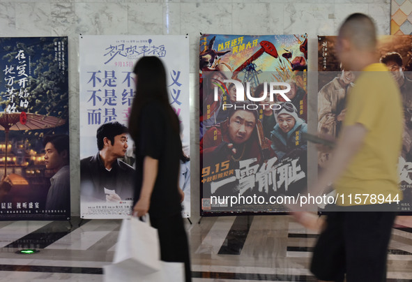 People walk past movie posters at a cinema in Fuyang, China, on September 16, 2024. 