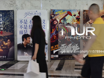 People walk past movie posters at a cinema in Fuyang, China, on September 16, 2024. (