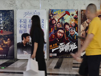 People walk past movie posters at a cinema in Fuyang, China, on September 16, 2024. (