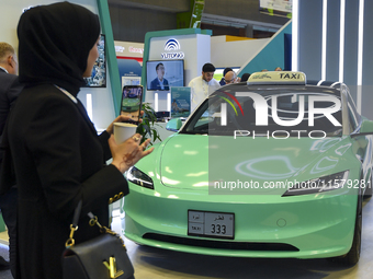 A visitor takes a picture of a Tesla taxi car at the Qatar Mowasalat Pavilion at the ConteQ Expo24 (Advanced Technology for Construction & S...