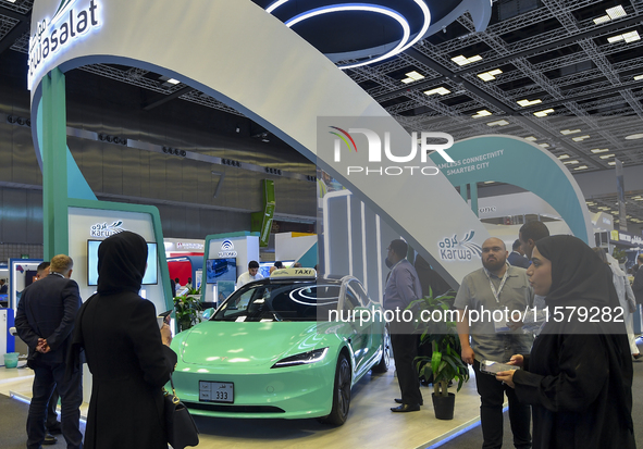 A visitor takes a picture of a Tesla taxi car at the Qatar Mowasalat Pavilion at the ConteQ Expo24 (Advanced Technology for Construction & S...