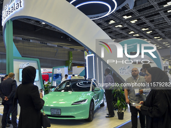 A visitor takes a picture of a Tesla taxi car at the Qatar Mowasalat Pavilion at the ConteQ Expo24 (Advanced Technology for Construction & S...